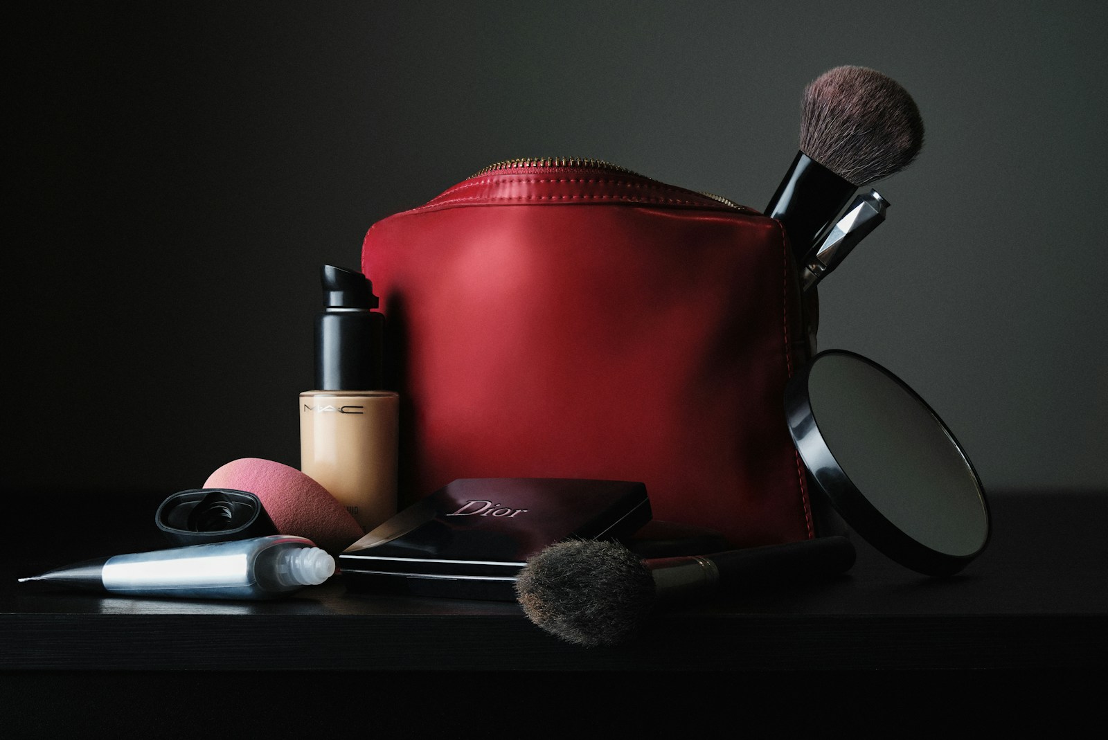 red leather bag beside black makeup brush